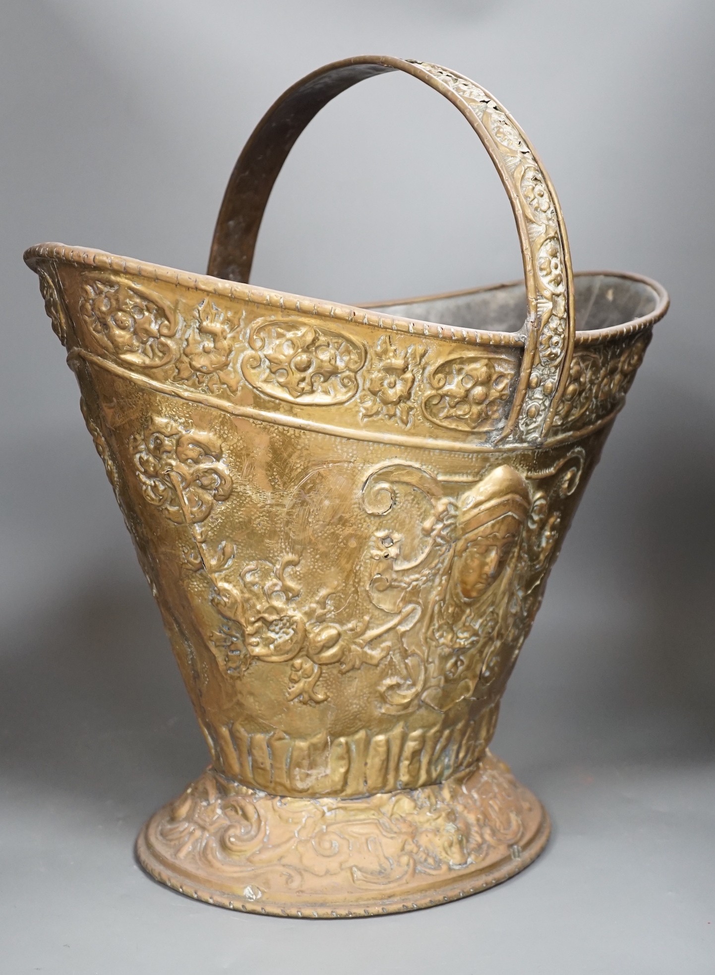 An embossed brass helmet coal bucket, 48cms high